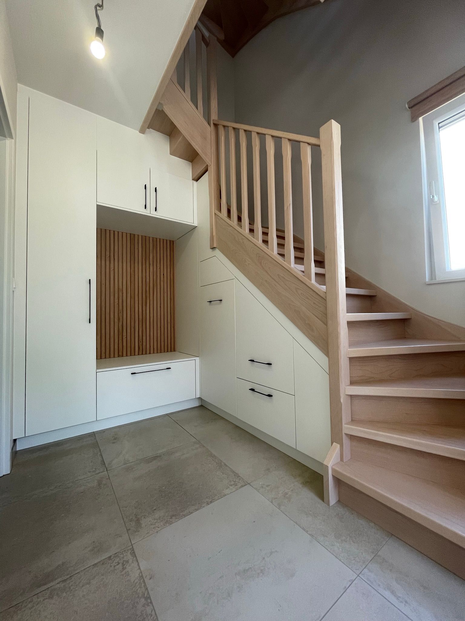 Aménagement sous escalier sur mesure avec placards, tiroirs et vestiaire
